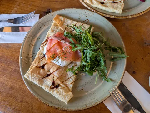 Une galette garnie de saumon et de roquette, servie à l’assiette
