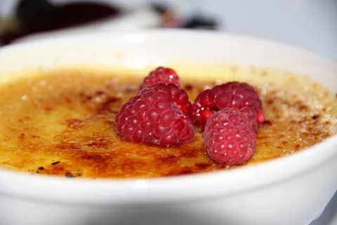 Une crème brûlée caramélisée, garnie de framboises
